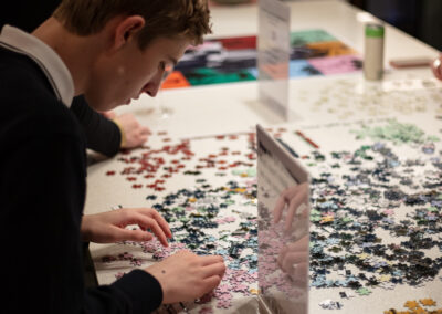 Photo of Celebration of Design attendees working on a large puzzle of the event poster